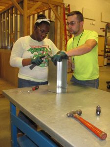 A career fair attendee builds a sheet metal toolbox with the help of a Sheet Metal Worker Local 24 journeyman.
